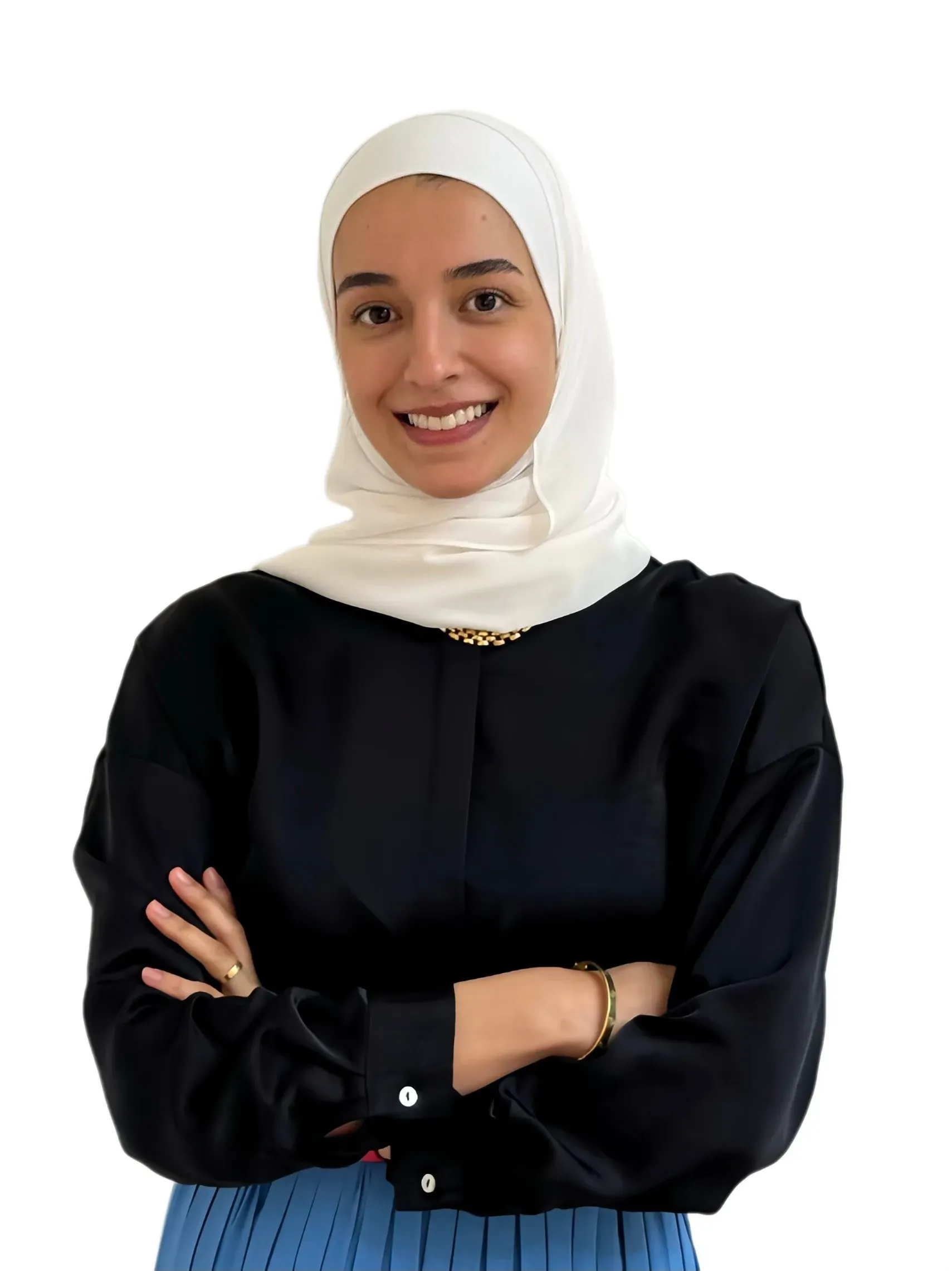 IMG_3959 - Perfect Balance Rehabilitation Centre Portrait of a smiling woman wearing a white hijab and black top with a blue pleated skirt, arms crossed against a white background.